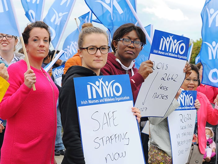 INMO members on a picket line hold INMO flags and posters